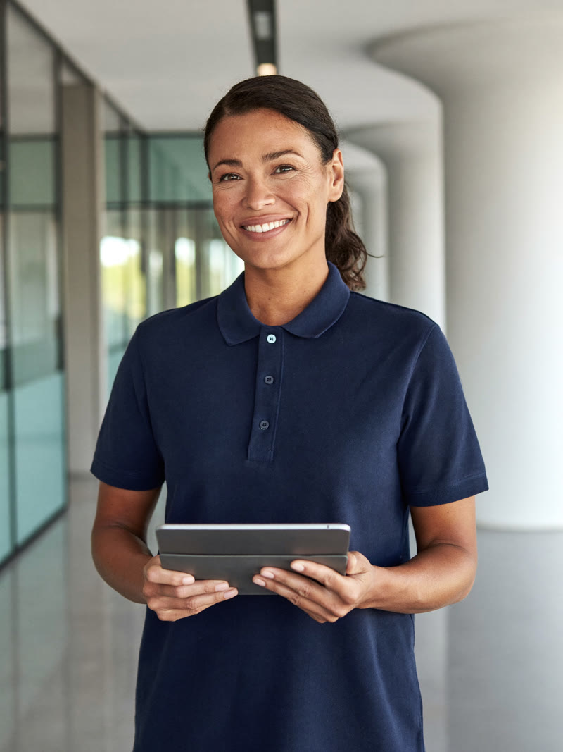 Freundliche Ansprechpartnerin mit Tablet in einem modernen Bürogebäude