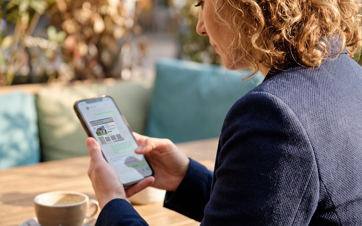 Eine Frau sieht sich im Café eine Firmen-Webseite auf dem Handy an