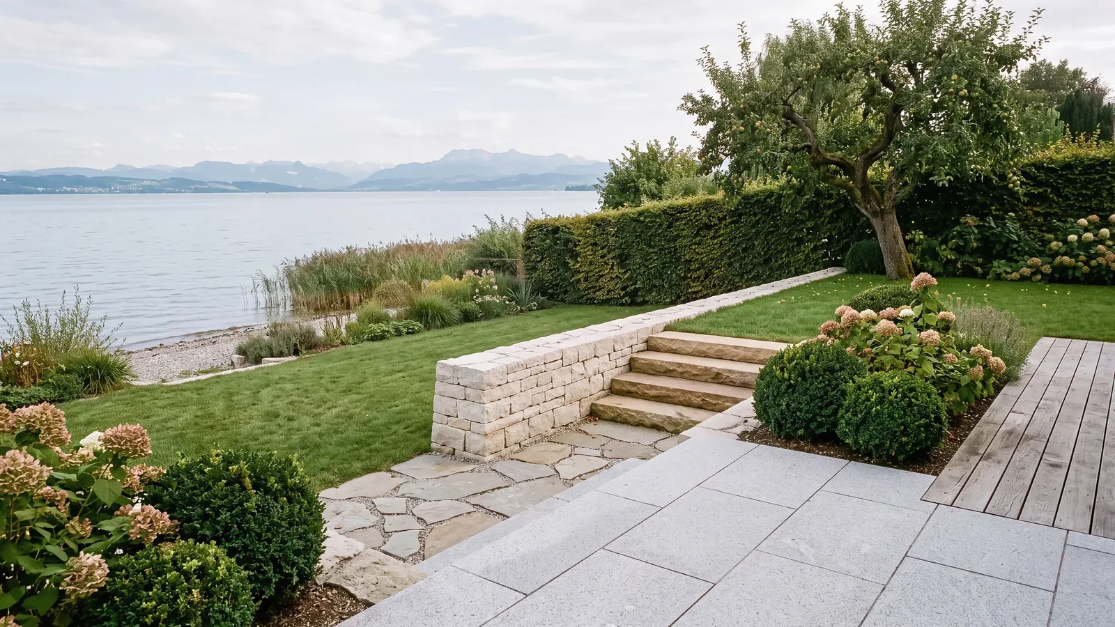 Trockenmauer aus hellem Kalkstein mit Sandsteintreppe und Terrasse aus Granitplatten am See