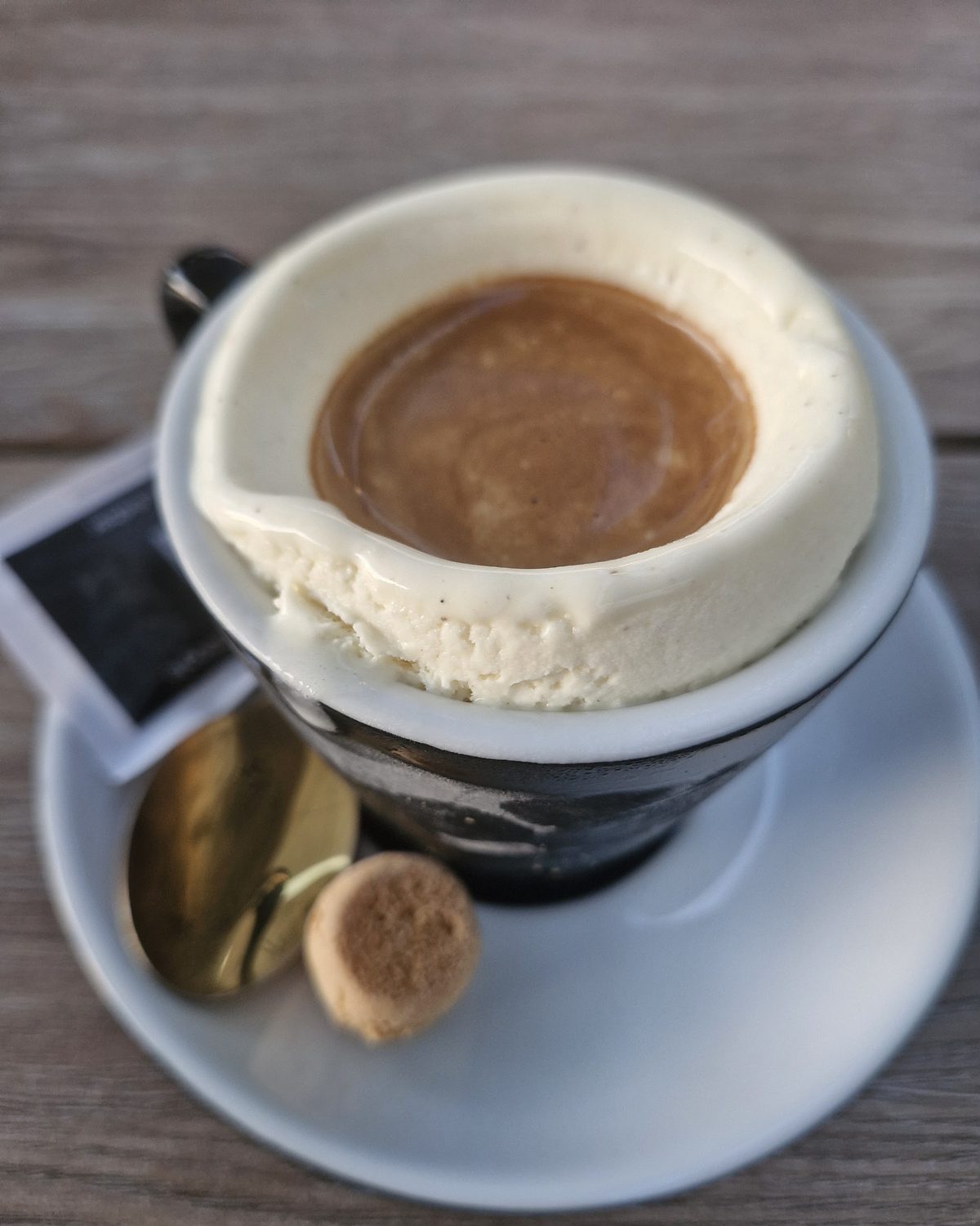 Affogato: Espresso über Vanilleeis in der Tasse, daneben ein Amarettino