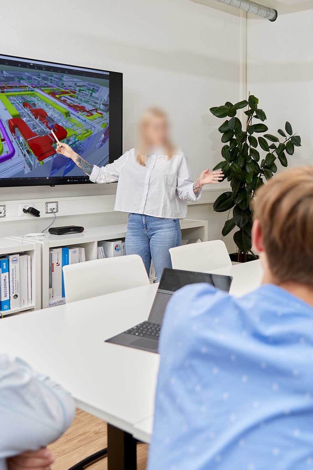 Besprechung bei Engineering Büro: eine Mitarbeiterin erklärt dem Team ein BIM-Modell am Bildschirm