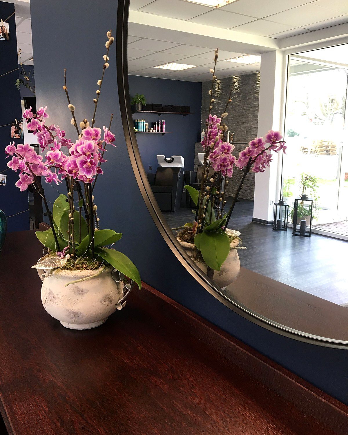 Orchidee auf dem Holztresen vor einem runden Spiegel