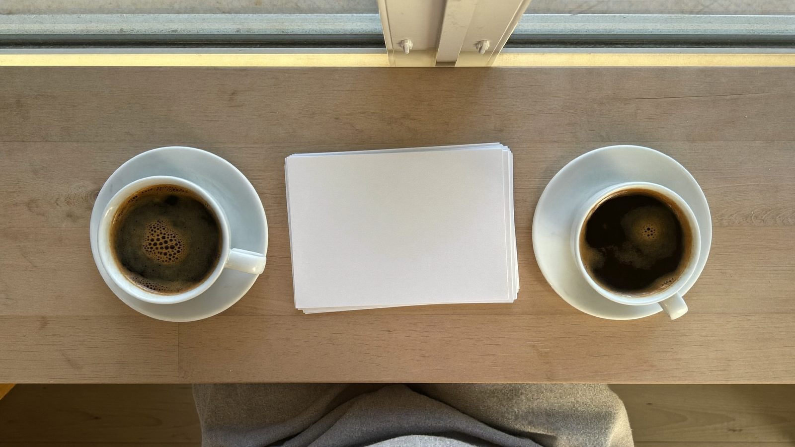 Zwei Tassen Kaffee und geordnete Unterlagen auf einem Beratungstisch